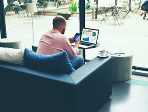 A person is sitting on sofa and using phone and laptop and learn english